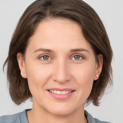 Joyful white young-adult female with medium  brown hair and grey eyes