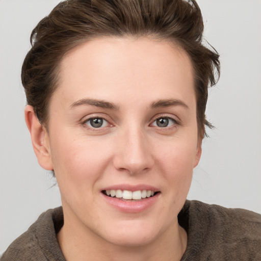 Joyful white young-adult female with short  brown hair and grey eyes