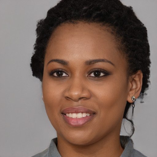 Joyful black young-adult female with long  black hair and brown eyes