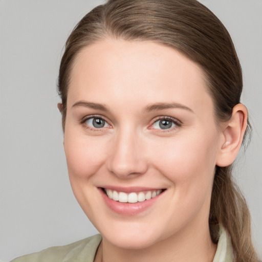 Joyful white young-adult female with medium  brown hair and grey eyes