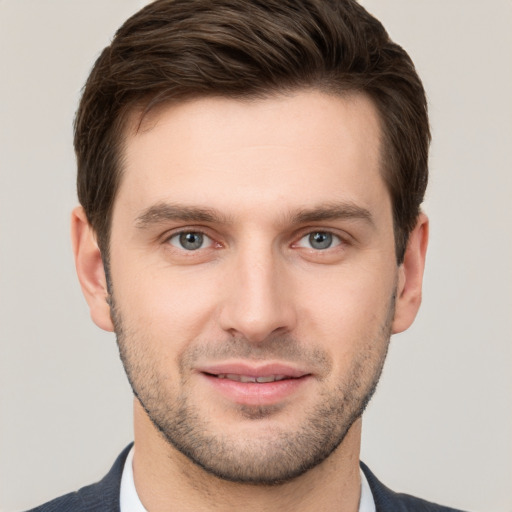 Joyful white young-adult male with short  brown hair and grey eyes