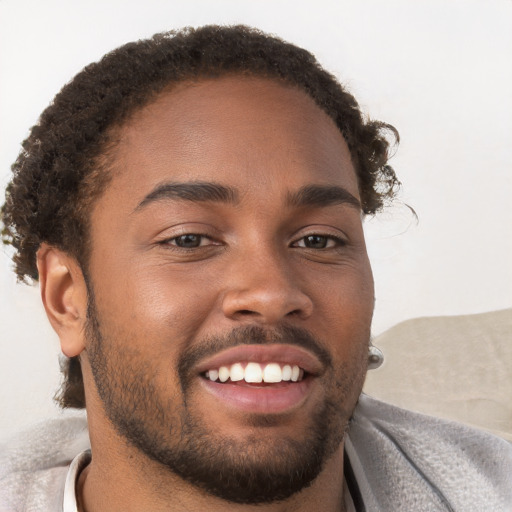 Joyful black young-adult male with short  brown hair and brown eyes