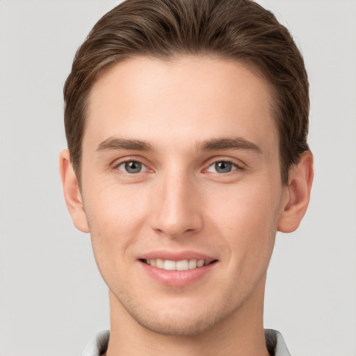 Joyful white young-adult male with short  brown hair and grey eyes