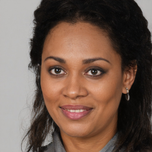 Joyful black young-adult female with long  brown hair and brown eyes