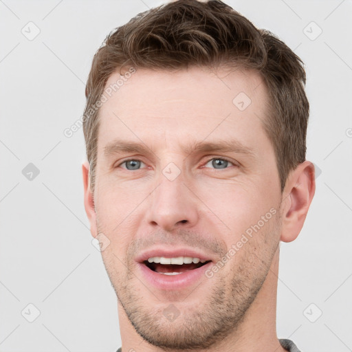 Joyful white young-adult male with short  brown hair and grey eyes