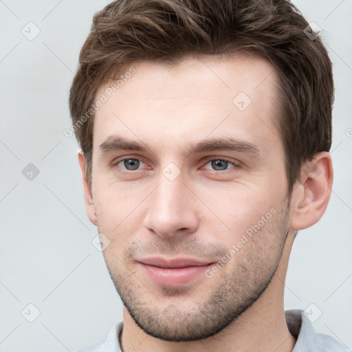 Joyful white young-adult male with short  brown hair and grey eyes