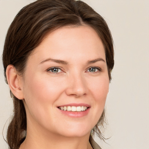 Joyful white young-adult female with medium  brown hair and grey eyes