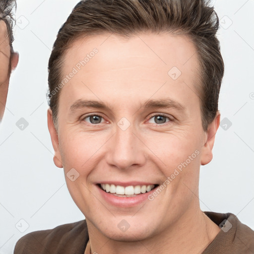 Joyful white young-adult male with short  brown hair and grey eyes