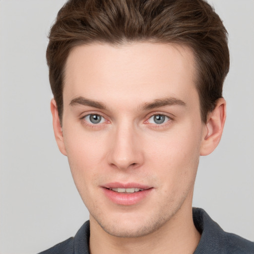 Joyful white young-adult male with short  brown hair and grey eyes