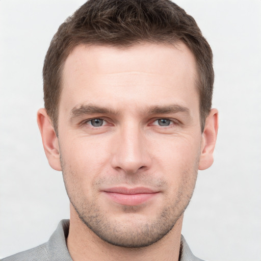 Joyful white young-adult male with short  brown hair and grey eyes