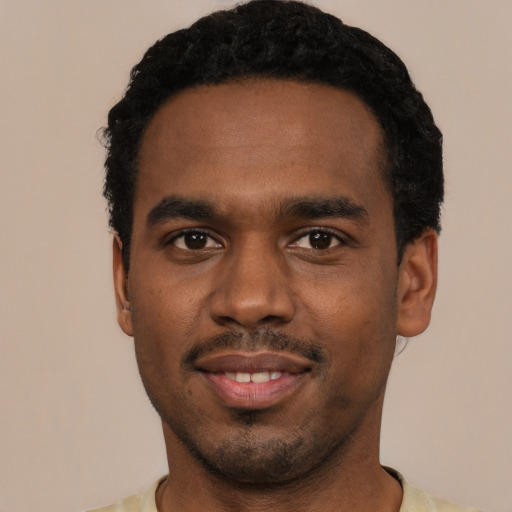 Joyful black young-adult male with short  black hair and brown eyes