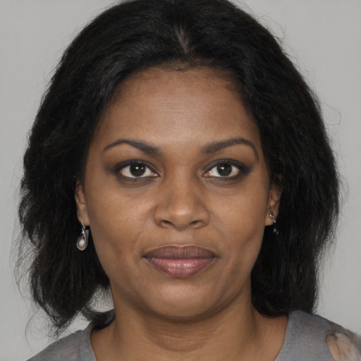 Joyful black young-adult female with long  brown hair and brown eyes