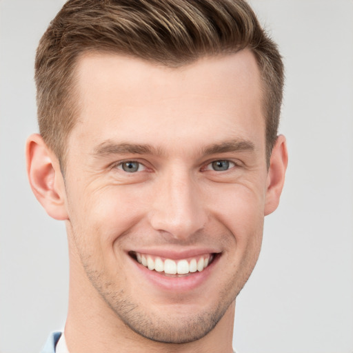 Joyful white young-adult male with short  brown hair and grey eyes