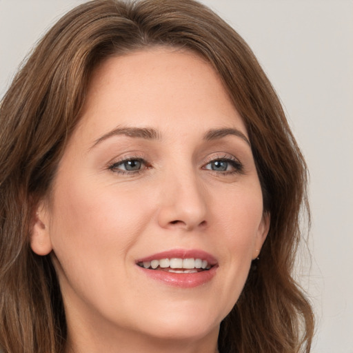 Joyful white young-adult female with long  brown hair and brown eyes