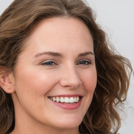 Joyful white young-adult female with long  brown hair and grey eyes