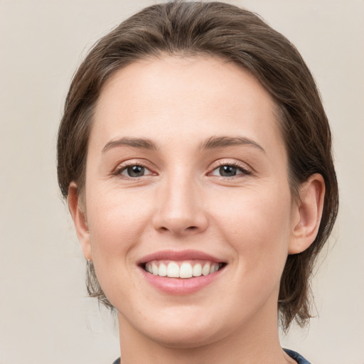 Joyful white young-adult female with medium  brown hair and grey eyes