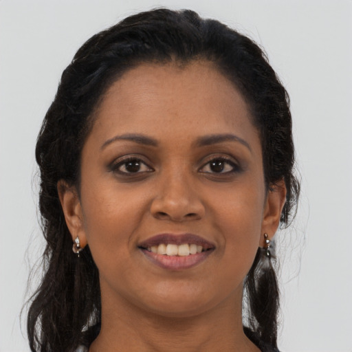 Joyful black young-adult female with long  brown hair and brown eyes