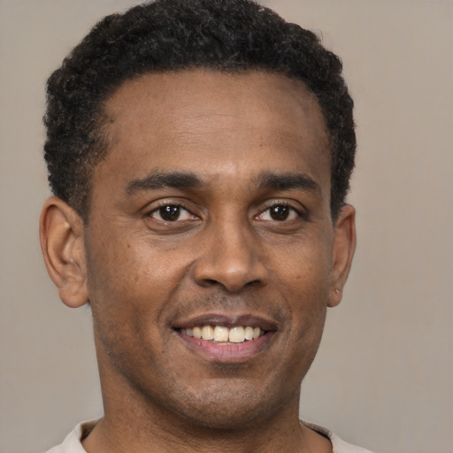 Joyful black young-adult male with short  brown hair and brown eyes