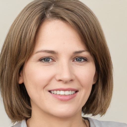 Joyful white young-adult female with medium  brown hair and grey eyes