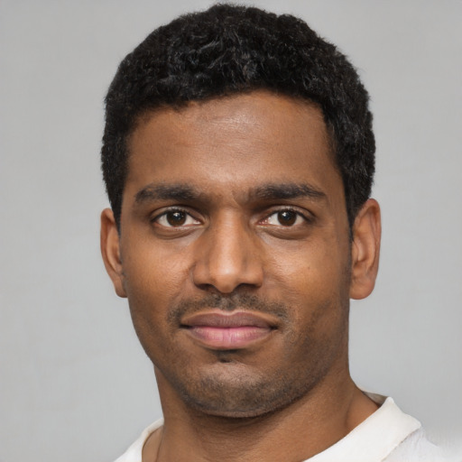 Joyful black young-adult male with short  black hair and brown eyes