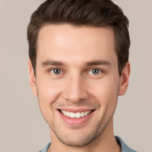 Joyful white young-adult male with short  brown hair and grey eyes