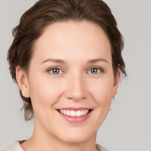 Joyful white young-adult female with medium  brown hair and grey eyes