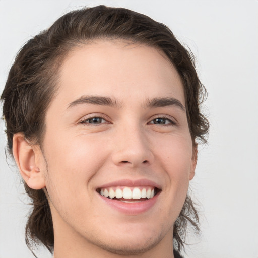 Joyful white young-adult male with long  brown hair and brown eyes