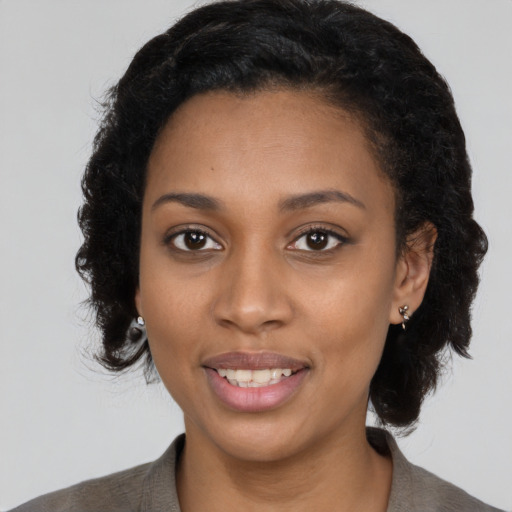 Joyful black young-adult female with long  black hair and brown eyes