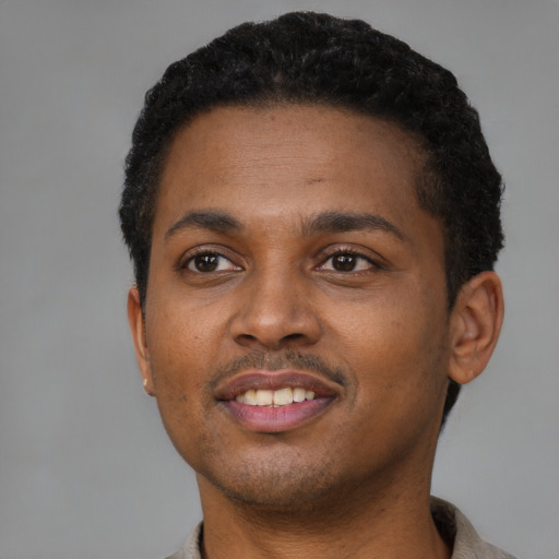 Joyful black young-adult male with short  brown hair and brown eyes