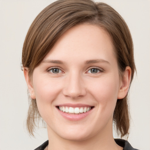 Joyful white young-adult female with medium  brown hair and grey eyes