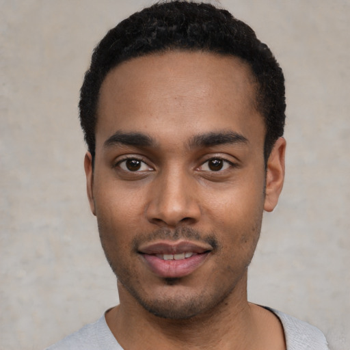 Joyful black young-adult male with short  black hair and brown eyes