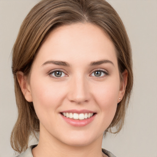 Joyful white young-adult female with medium  brown hair and grey eyes