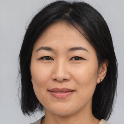 Joyful asian adult female with medium  brown hair and brown eyes