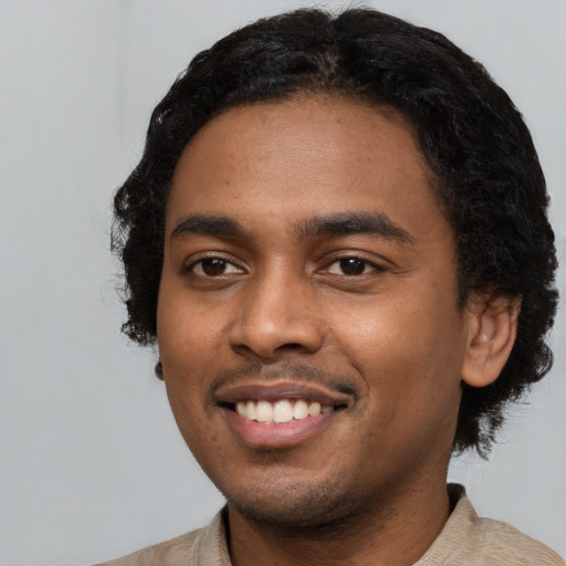 Joyful black young-adult male with short  black hair and brown eyes