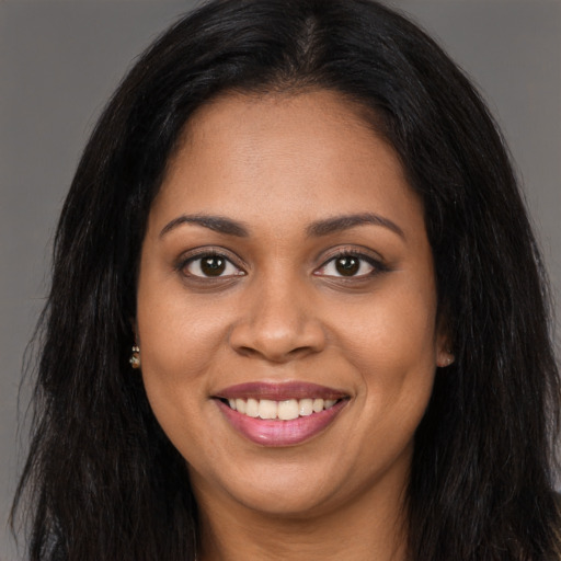 Joyful black young-adult female with long  brown hair and brown eyes