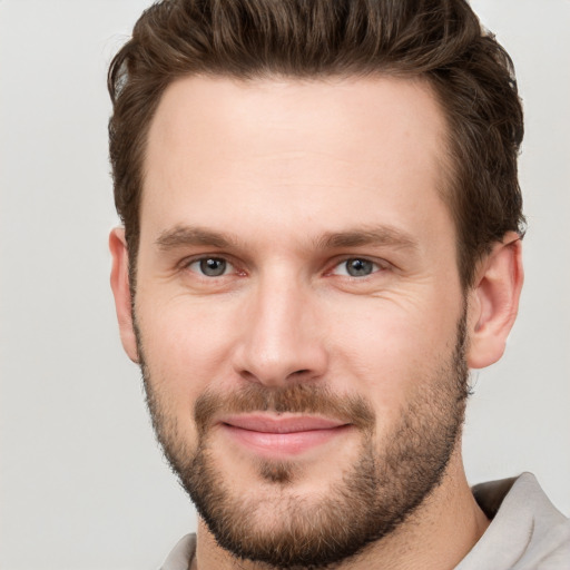 Joyful white young-adult male with short  brown hair and grey eyes