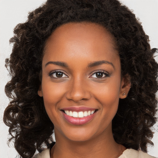 Joyful black young-adult female with long  brown hair and brown eyes