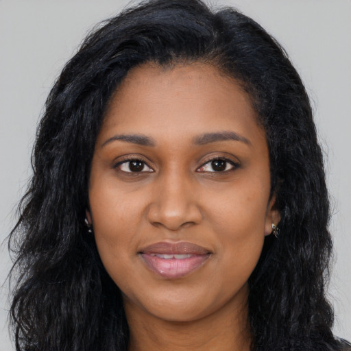 Joyful black young-adult female with long  black hair and brown eyes