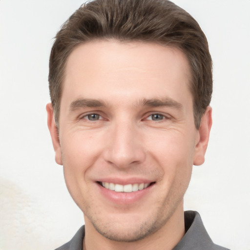 Joyful white young-adult male with short  brown hair and grey eyes