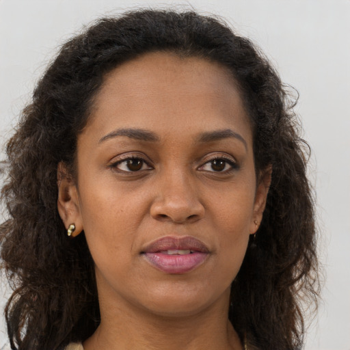 Joyful black adult female with long  brown hair and brown eyes