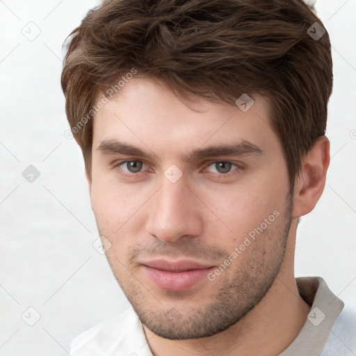 Joyful white young-adult male with short  brown hair and grey eyes