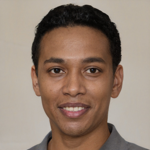Joyful black young-adult male with short  black hair and brown eyes