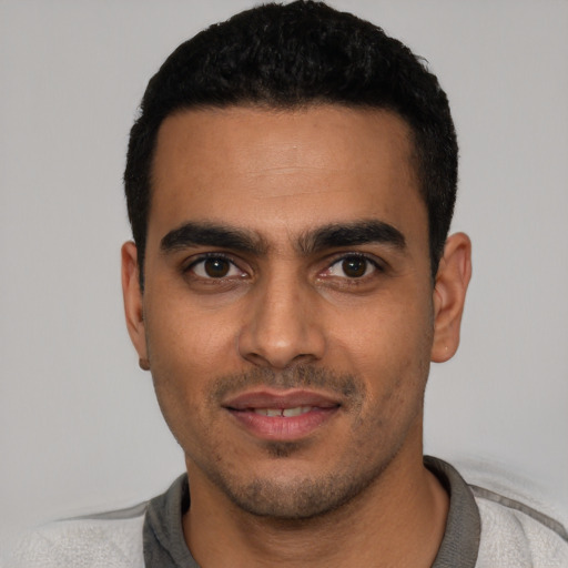 Joyful latino young-adult male with short  black hair and brown eyes