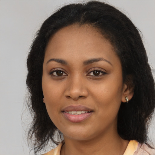 Joyful black young-adult female with long  brown hair and brown eyes