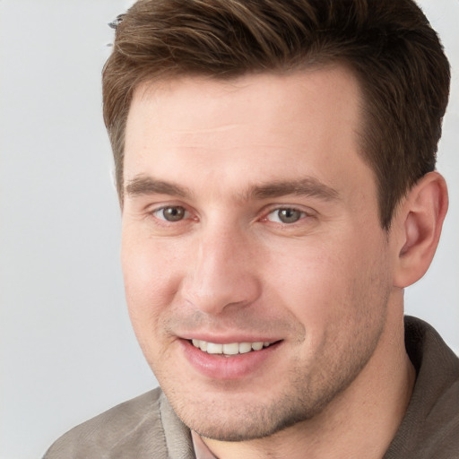 Joyful white young-adult male with short  brown hair and grey eyes