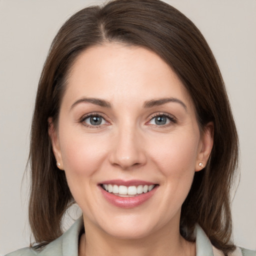 Joyful white young-adult female with medium  brown hair and grey eyes