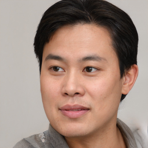 Joyful asian young-adult male with short  brown hair and brown eyes