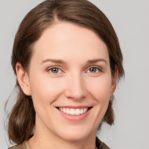 Joyful white young-adult female with medium  brown hair and grey eyes