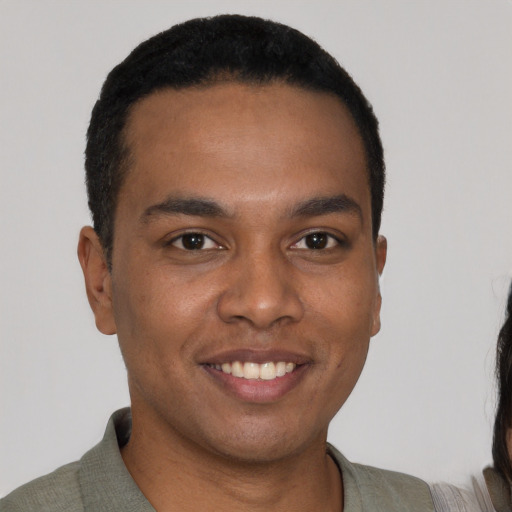 Joyful black young-adult male with short  black hair and brown eyes
