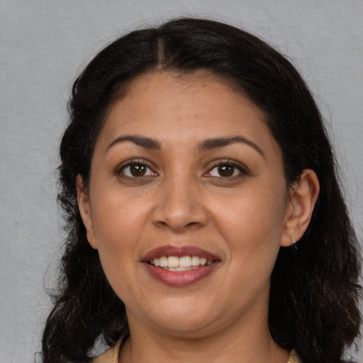 Joyful latino adult female with long  brown hair and brown eyes